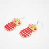 A pair of handmade ceramic earrings featuring a double-rounded shape, flowers in a vase. The top section is decorated with hand-painted colourful flowers, while the bottom section has a bold red checkered pattern. Finished with silver hooks.