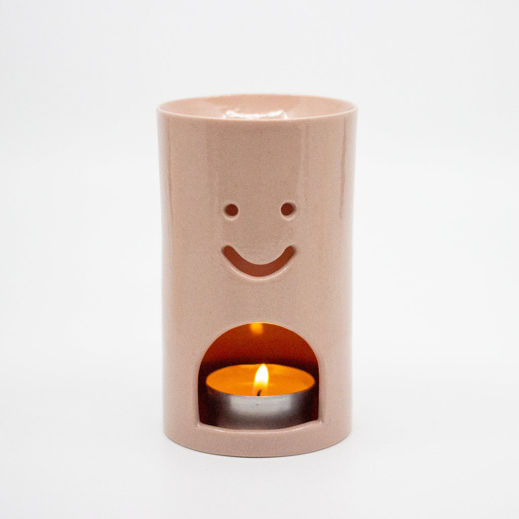 Ceramic oil burner with a smiley face design on a white background