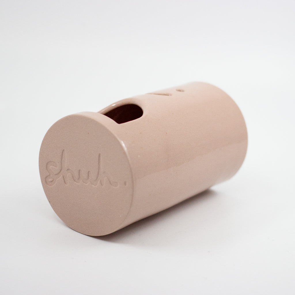 Pink cylindrical oil burner with 'shuh' branding on a white background
