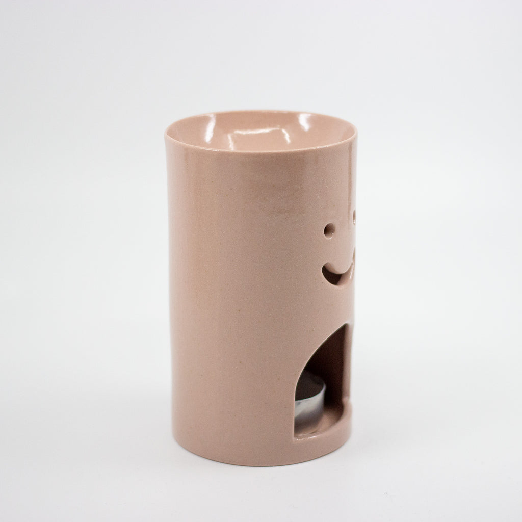 Pink ceramic oil burner with smiley face design on a white background