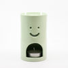 Light green oil burner with a smiley face design on a white background