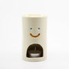 Ceramic oil burner with a smiley face design on a white background