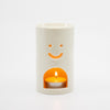 White ceramic oil burner with a smiley face design on a white background
