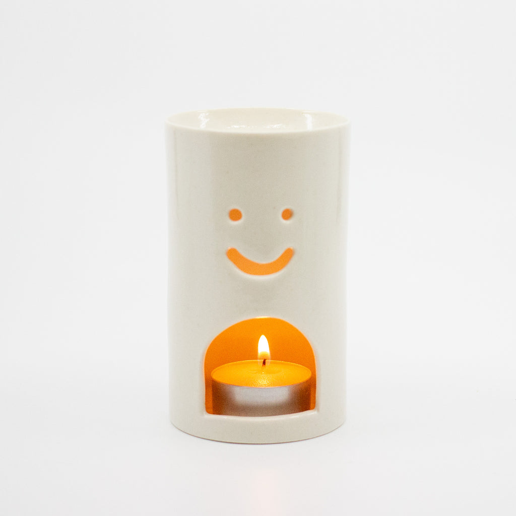 White ceramic oil burner with a smiley face design on a white background