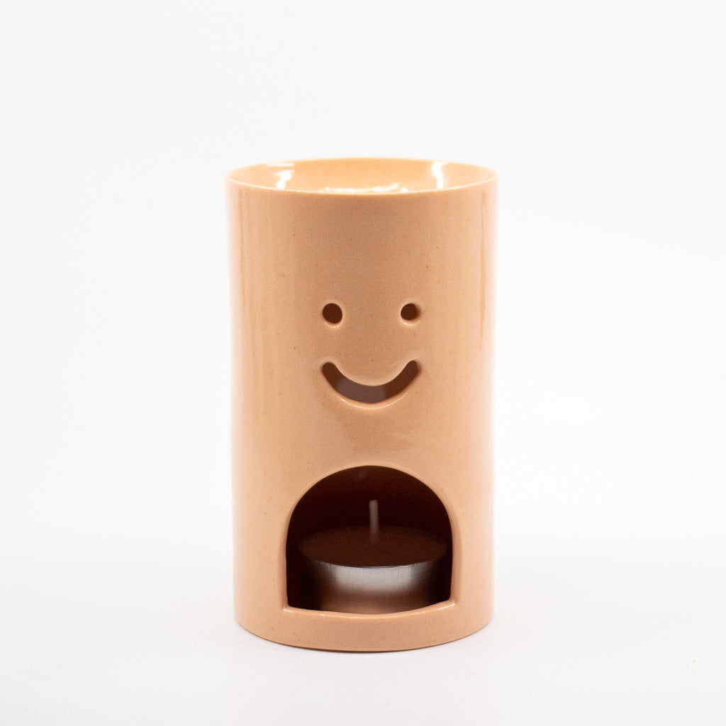Pastel Orange Ceramic oil burner with smiley face design on a white background