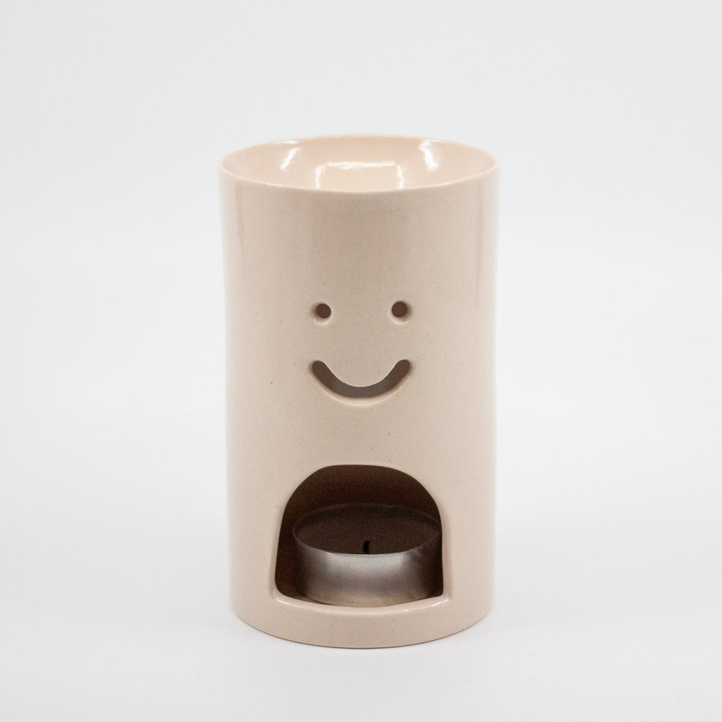 Pink ceramic oil burner with smiley face design on a white background
