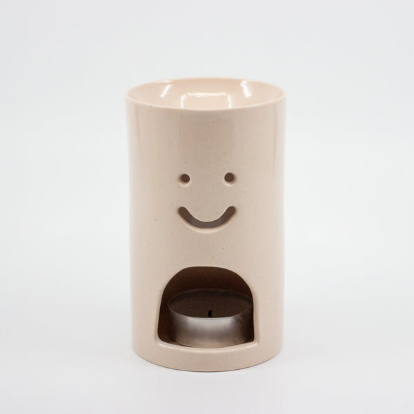 Pink ceramic oil burner with smiley face design on a white background