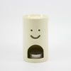 Cylindrical ceramic oil burner with a smiley face design on a white background