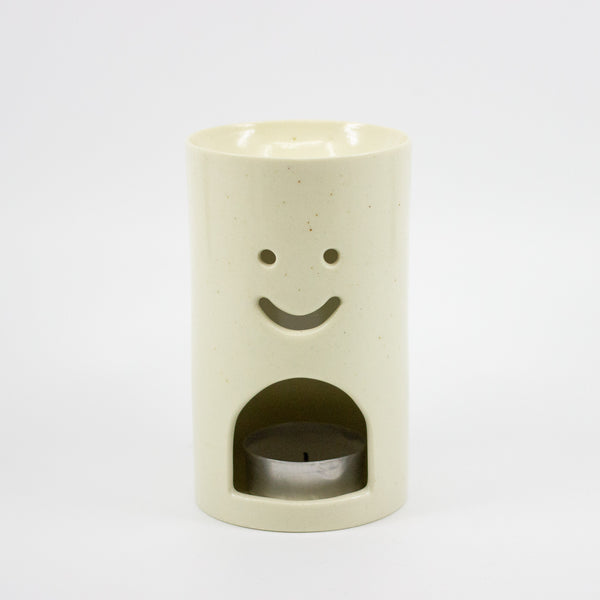 Cylindrical ceramic oil burner with a smiley face design on a white background