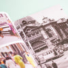 An open printed photo book spread, showing a black-and-white architectural street scene on the right page and colourful cropped photos on the left page, photographed against a pale mint background.