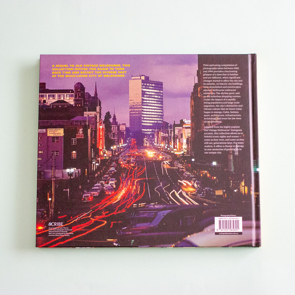 The back cover of a hardcover book, featuring a purple-toned photograph of a city street with long light trails from cars, set against a plain mint background.