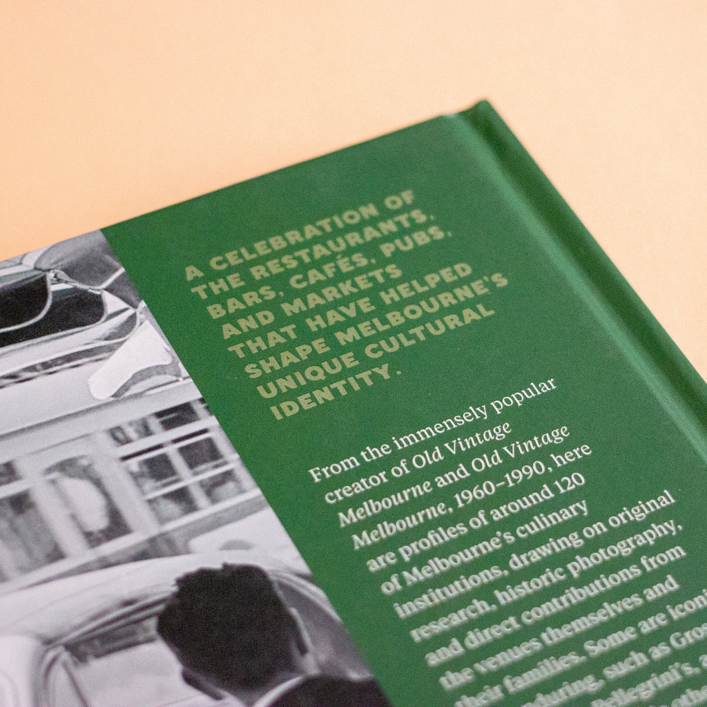 A close-up of a green book cover featuring white text and a black-and-white photograph, photographed on a warm beige background.