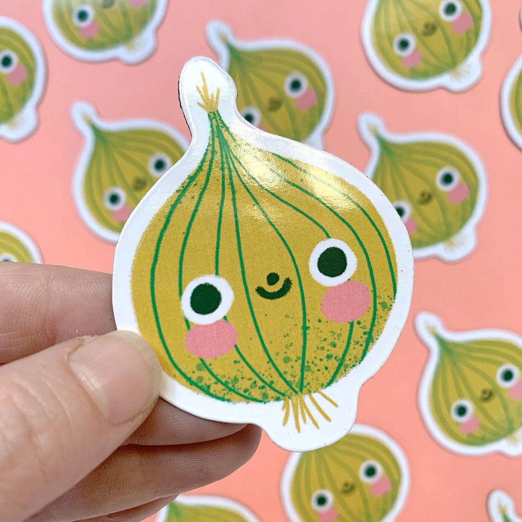 Sticker of a cartoon onion with a face held by a hand against a background of similar magnets.