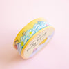 A roll of washi tape with a pastel yellow and cream background, decorated with cute cartoon characters and the words 'Party Piping' in black script, set against a soft pink background.