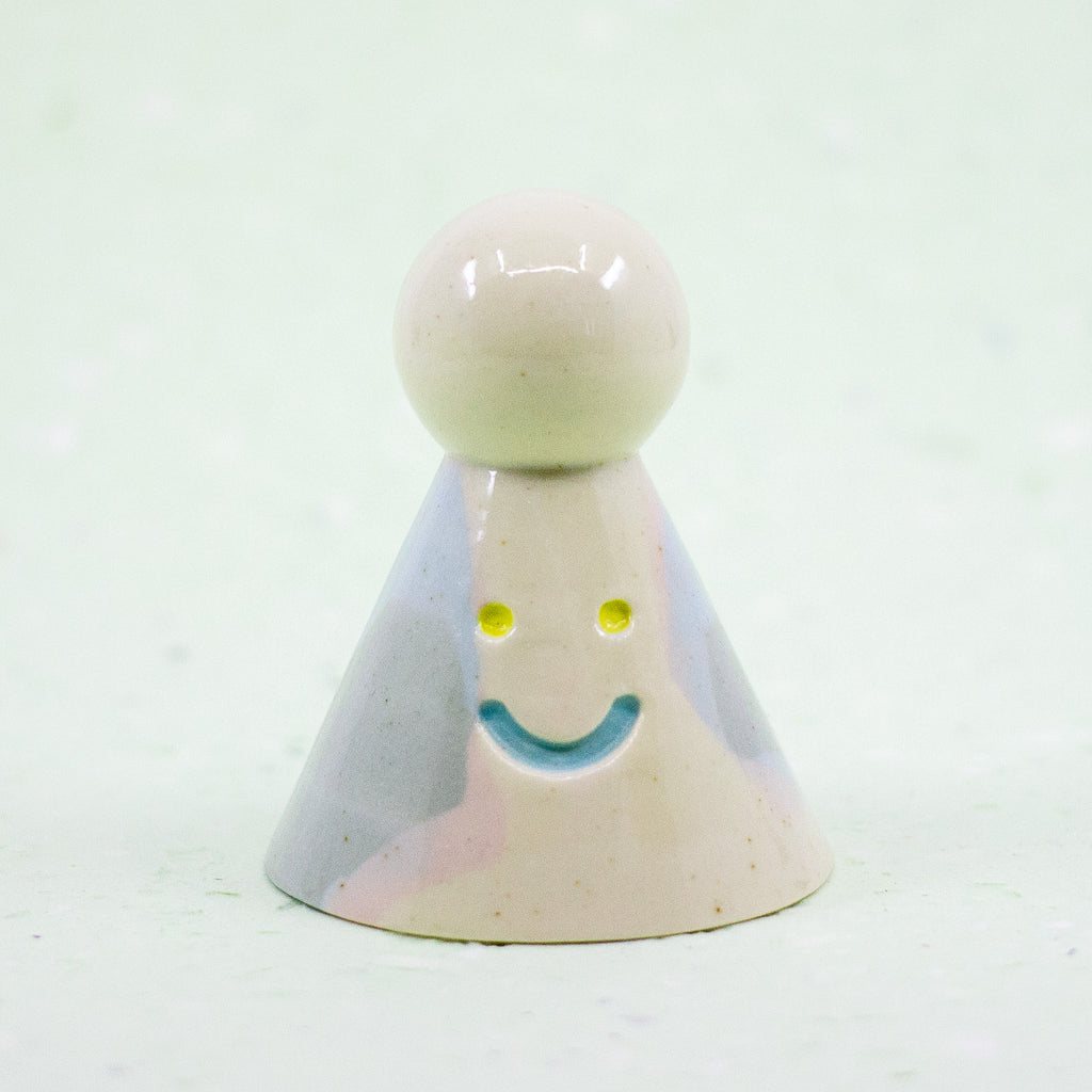 Small ceramic figure with a smiling face on a white background