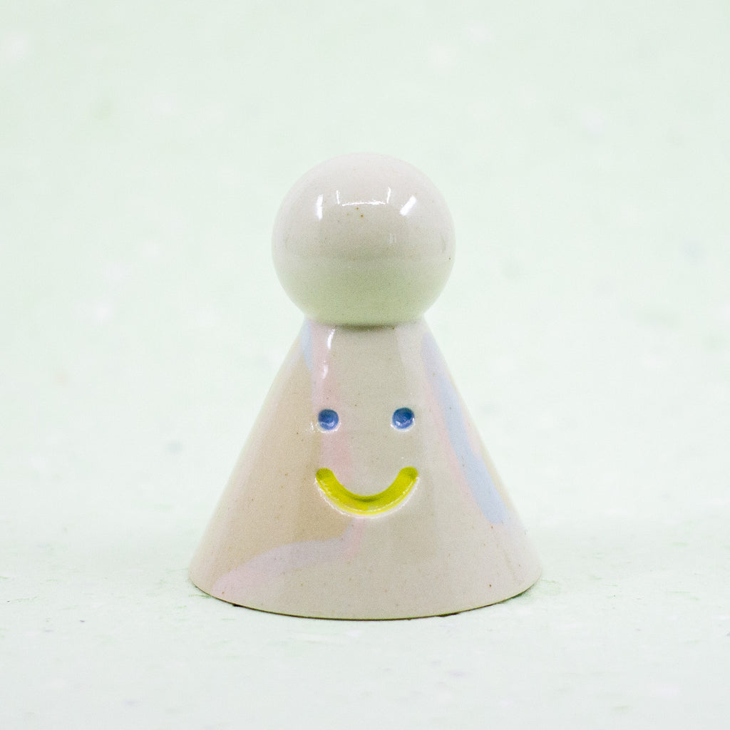 Small ceramic figure with a smiley face on a white background