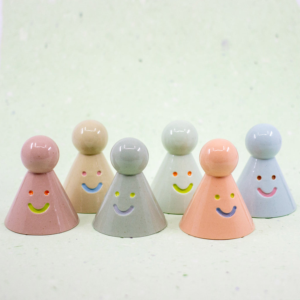 Set of six colorful ceramic figures with smiling faces on a light background