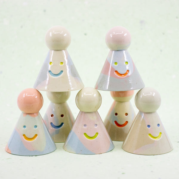 Set of colorful ceramic cone-shaped toys with smiling faces on a white background