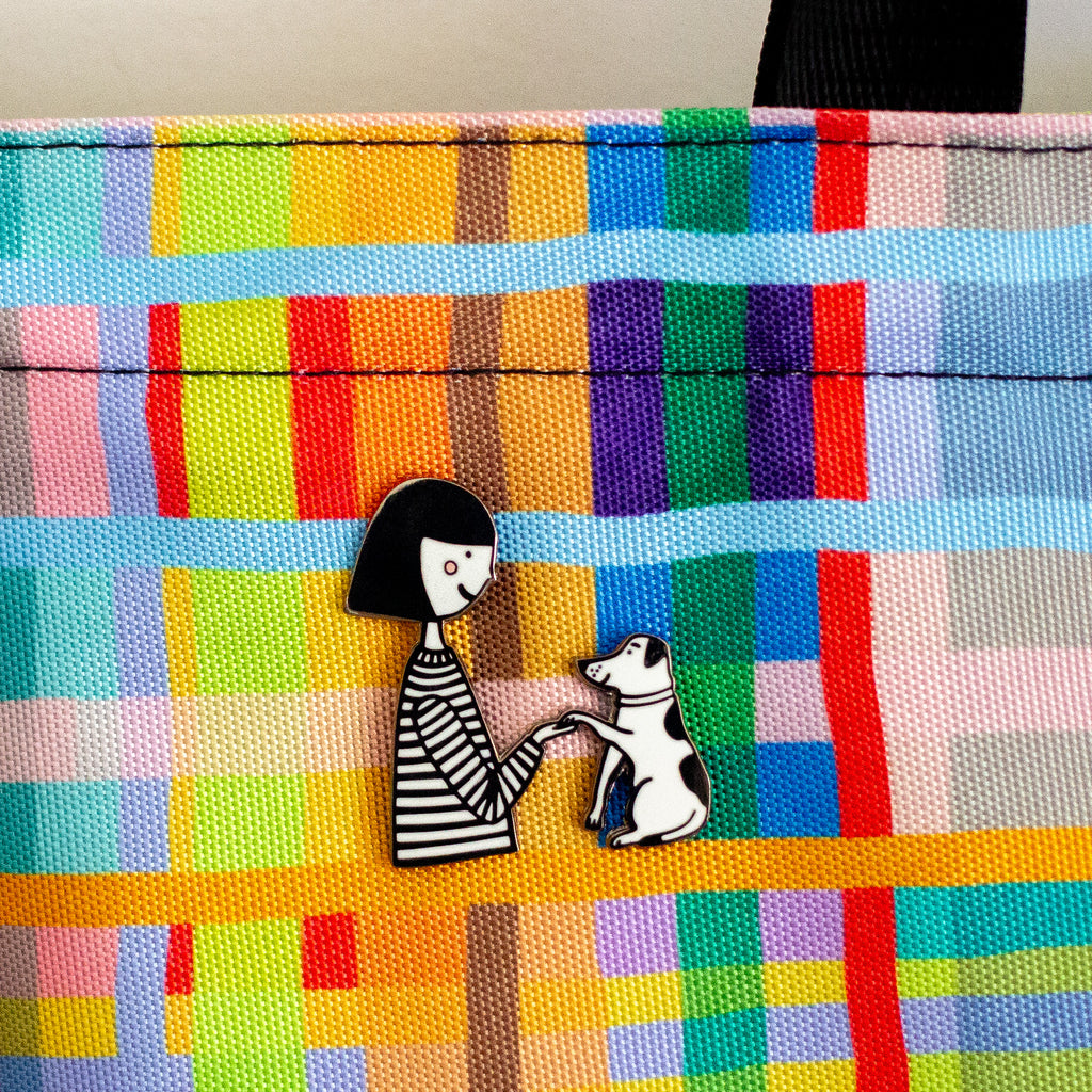 Colorful fabric with a pin of a woman and dog on a checkered pattern