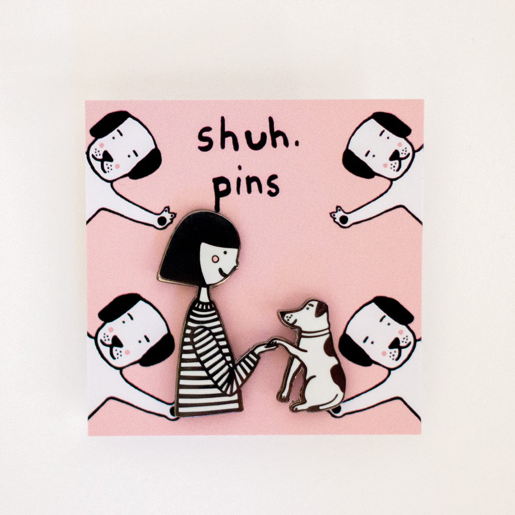 Enamel pins with a girl and dog character holding hands.