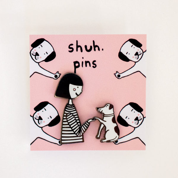 Enamel pins with a girl and dog character holding hands.