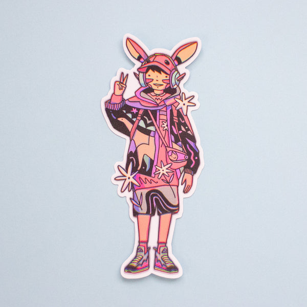 A die-cut vinyl sticker featuring a cartoon character with rabbit ears, a pink cap, headphones, and a colourful abstract outfit, shown on a light blue background.