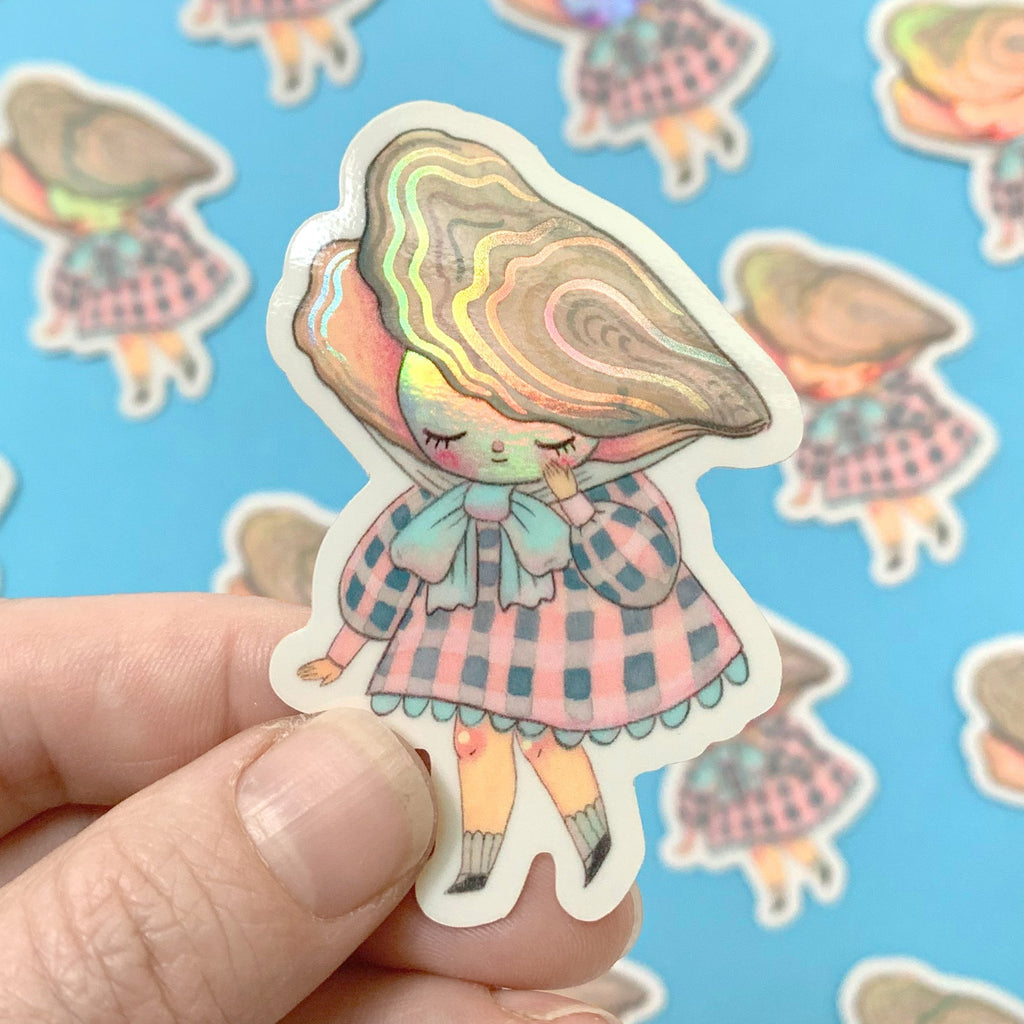 Holographic sticker of a character in a checkered dress and hat held by a hand against a blue background with more stickers.