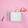 Open notebook with a keychain and ruler on a pink background