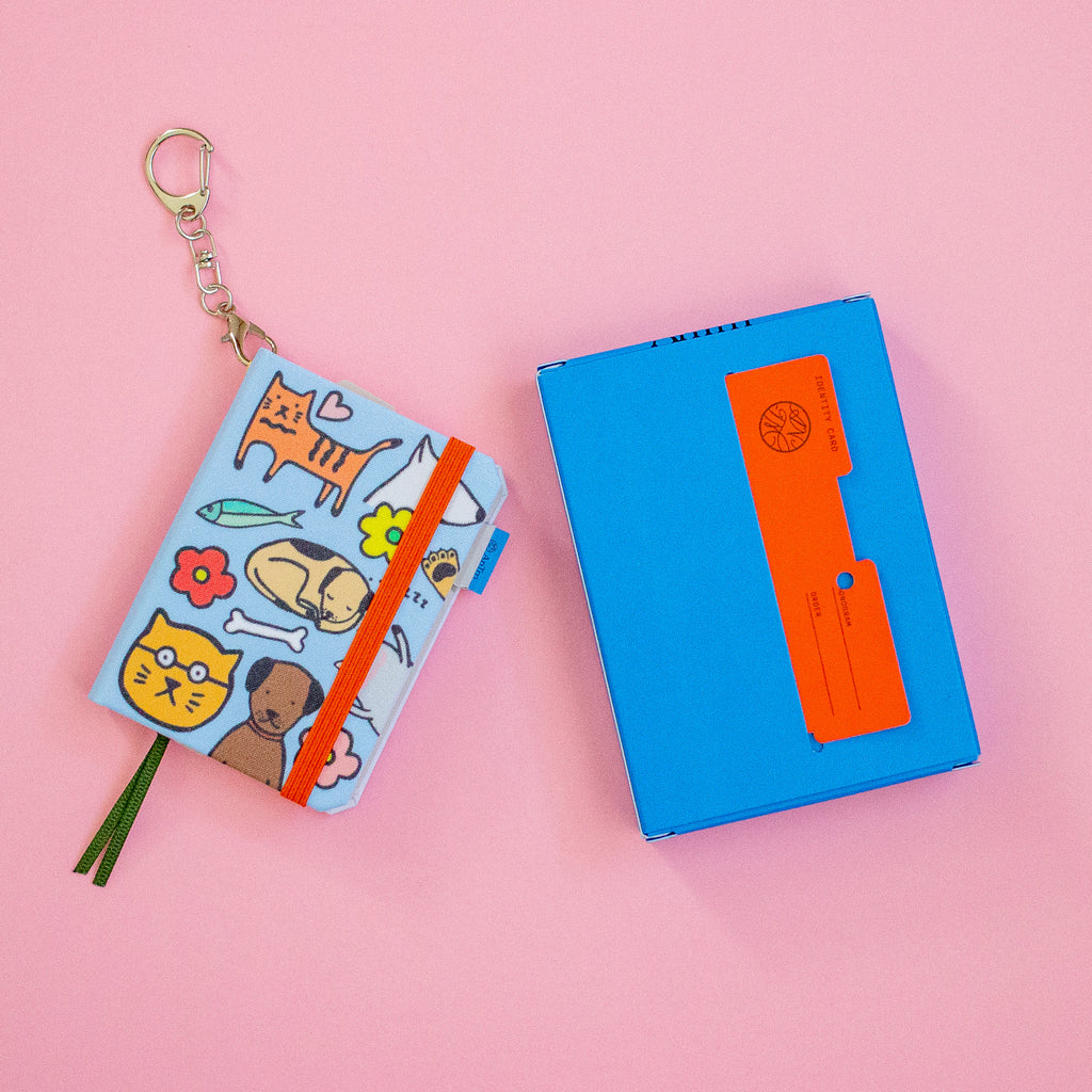 Small notebook with animal illustrations and a keychain on a pink background