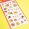 A sheet of cute cartoon stickers featuring yellow cats, strawberries, desserts, cherries, and the word 'LOVE' in letters, placed diagonally on a bright yellow background.