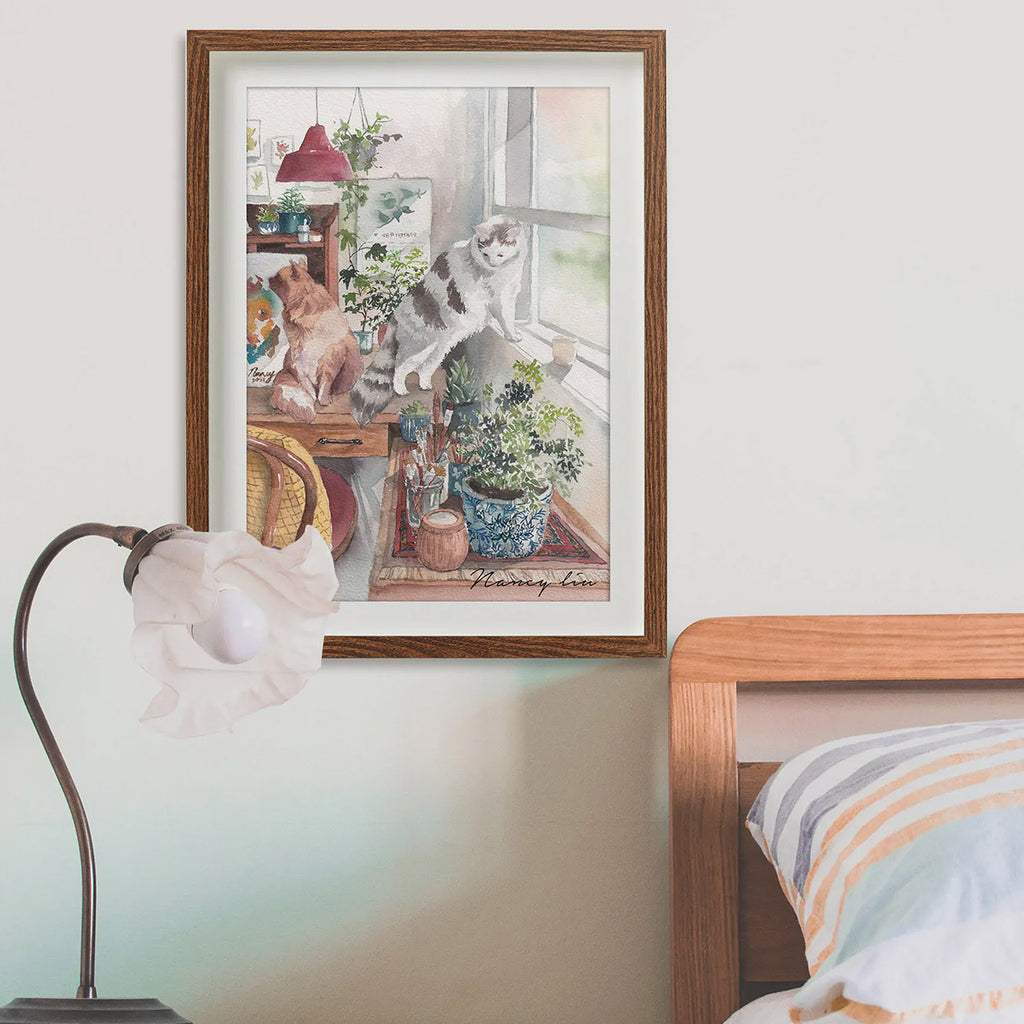 Framed artwork of cats by a window in a bedroom setting