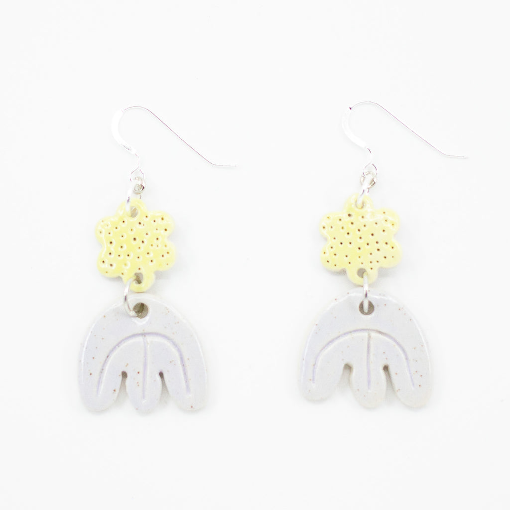 Photo of two earrings, with ceramic beads. First bead is daisy shaped with yellow colour and polka dots. 2nd attached bead is tulip shaped in natural glaze. Sterling silver hooks. 