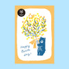 Postcard with a bear holding flowers and 'Happy Birthday!' text on a light blue background.