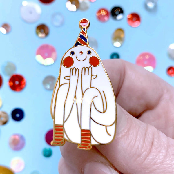 Hand holding a cartoonish ghost with a party hat against a colourful confetti background