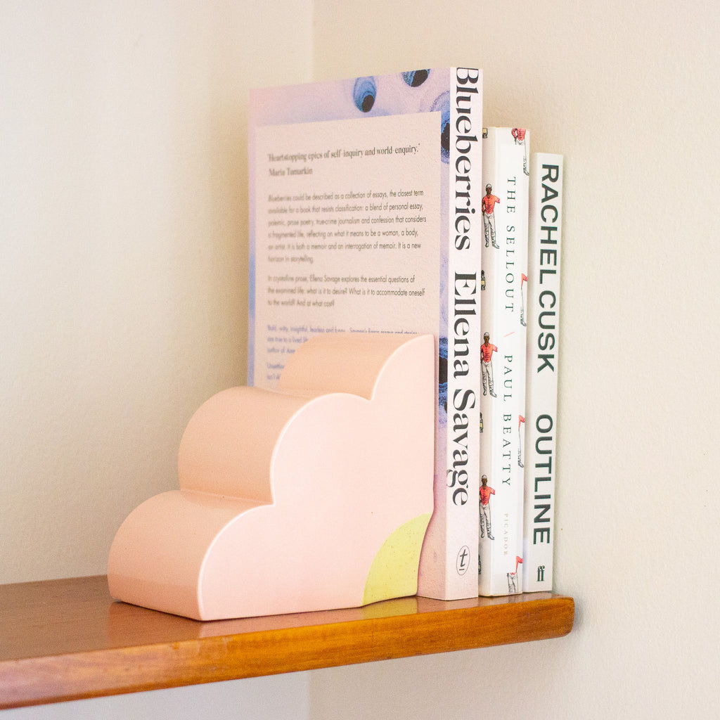 Quarter flower bookend in use holding up 3 books on a shelf. 