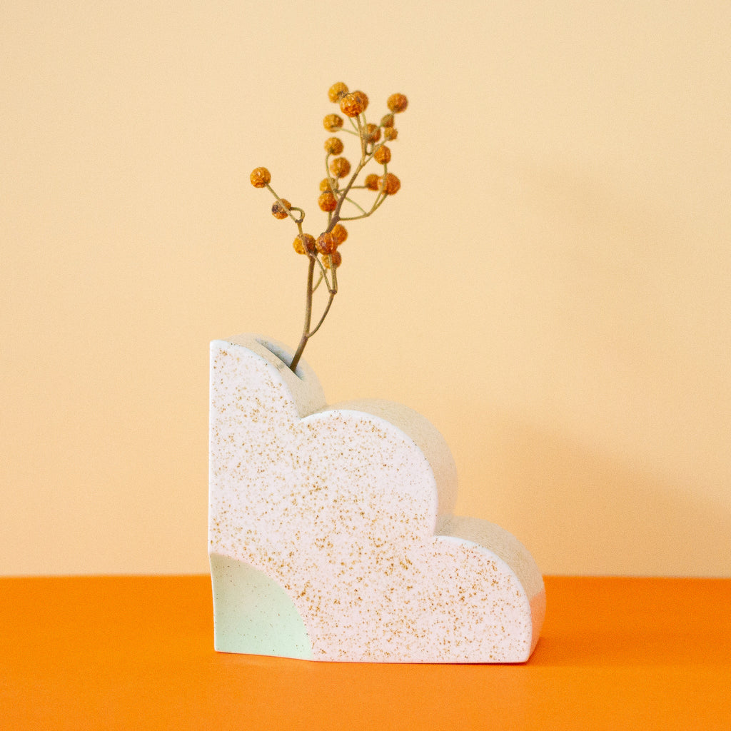 Ceramic bookend in the shape of a quarter of a flower. Opening at the top in which a flower is placed. Side view. 