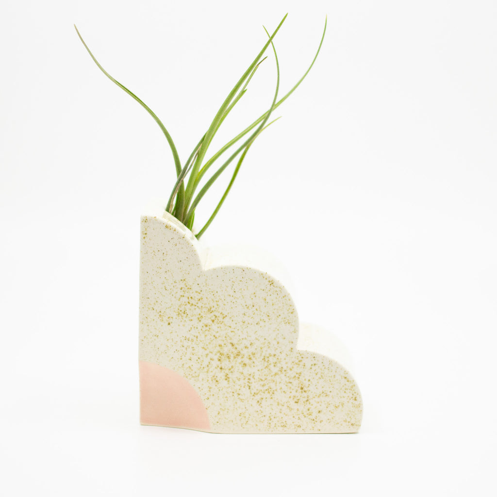 Ceramic bookend in a quarter flower shape. Speckled finish with pink highlight. Opening at top so bookend also functions as a vase. 