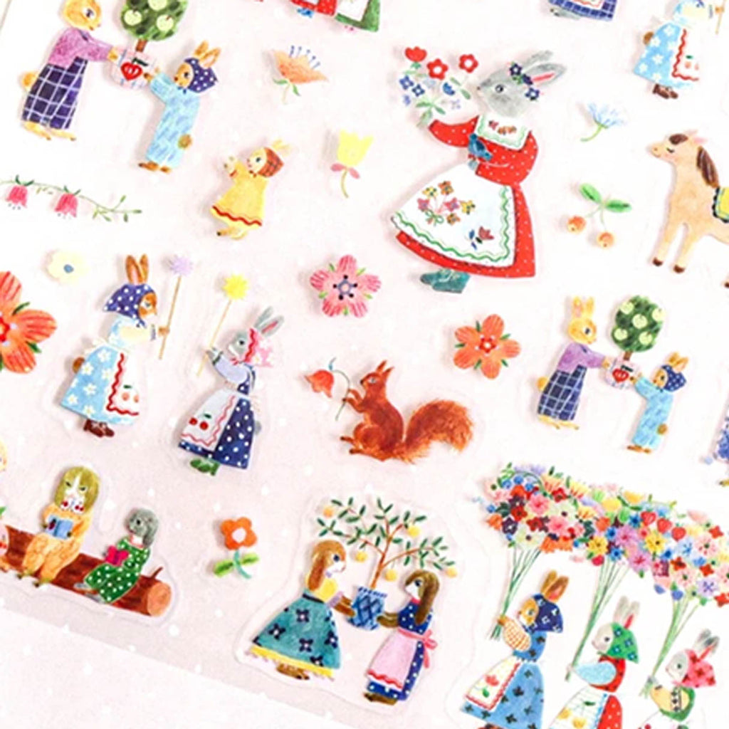 A close-up of a sticker sheet covered with colourful illustrations of rabbit and animal figures, flowers, and small woodland motifs in pastel and bright colours.