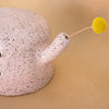 Closeup of the Rah figurine arm, which has a hole where you can place a flower. There is a stem and flower in the hole. 