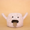 Front facing photo of the rah figurine. Artwork is made from stoneware clay with a pink glaze. Figurine has an open mouth with tongue hanging out, two eyes, and two hands that are extended. 