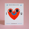 A square white art print or card featuring a stylized red heart with black eyes and a blue smile, with the text 'Illustrated in Melbourne with love.' and '@samanthacurcio' on a soft pink background.