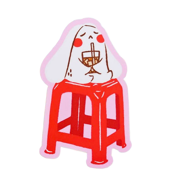 A die-cut sticker featuring a cartoon illustration of a white rabbit sitting on a red stool and holding a wine glass, set against a plain white background.