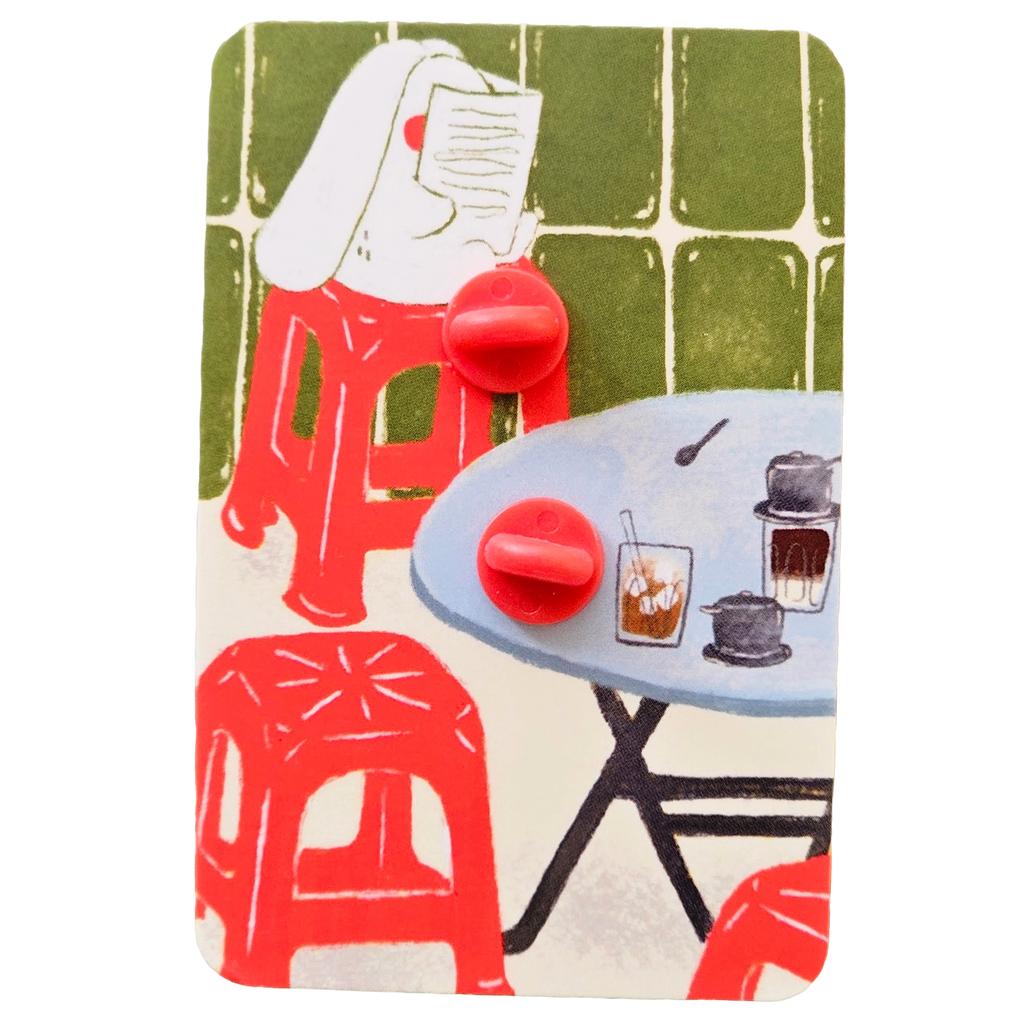The back of enamel pin packaging with two red rubber stopper, mounted on its illustrated backing card.