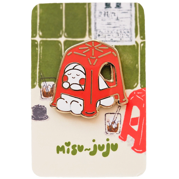 A Misu Juju enamel pin shaped like a red plastic stool with a cute cartoon character inside, mounted on its illustrated backing card.