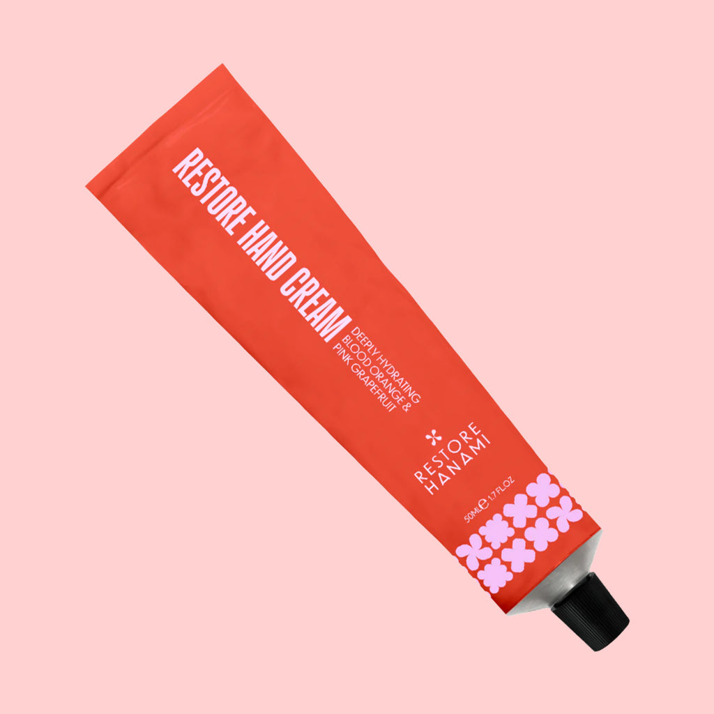 Red tube of 'Restore Hand Cream' on a pink background