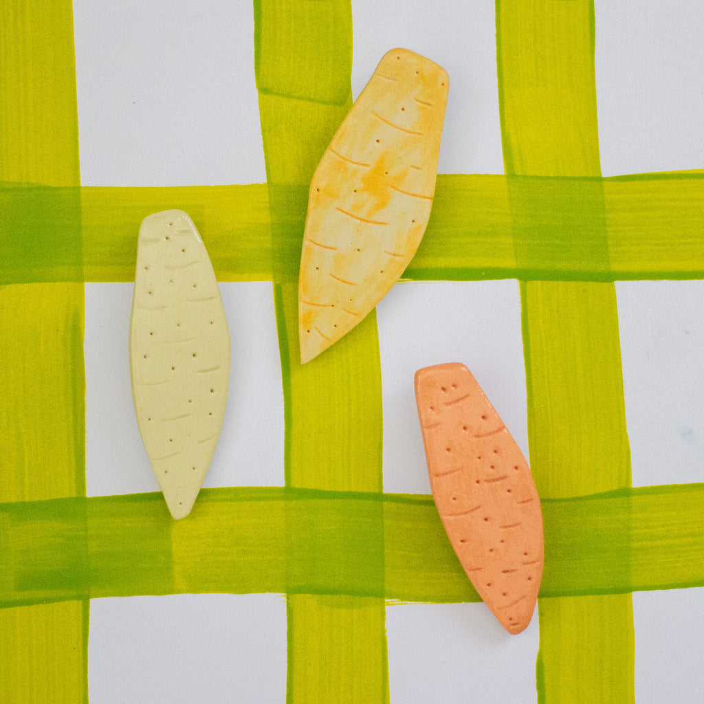 Three vegetable-shaped cookies on a green and white background