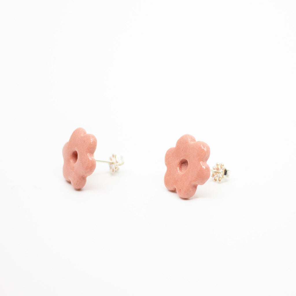Pink flower-shaped earrings on a white background