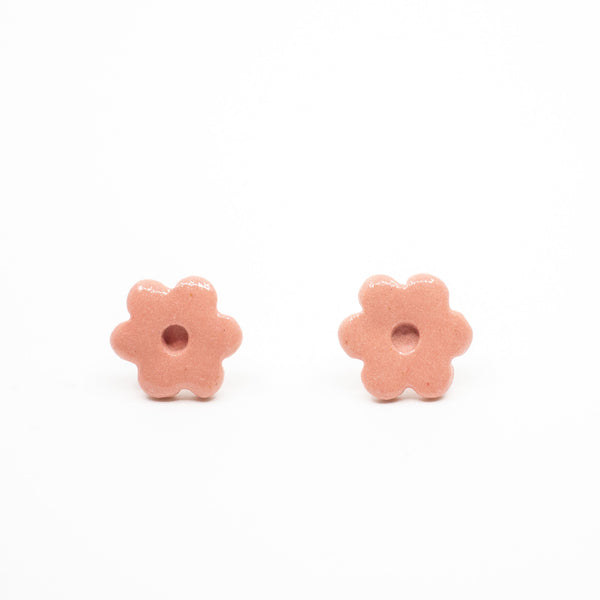 Two pink flower-shaped earrings on a white background