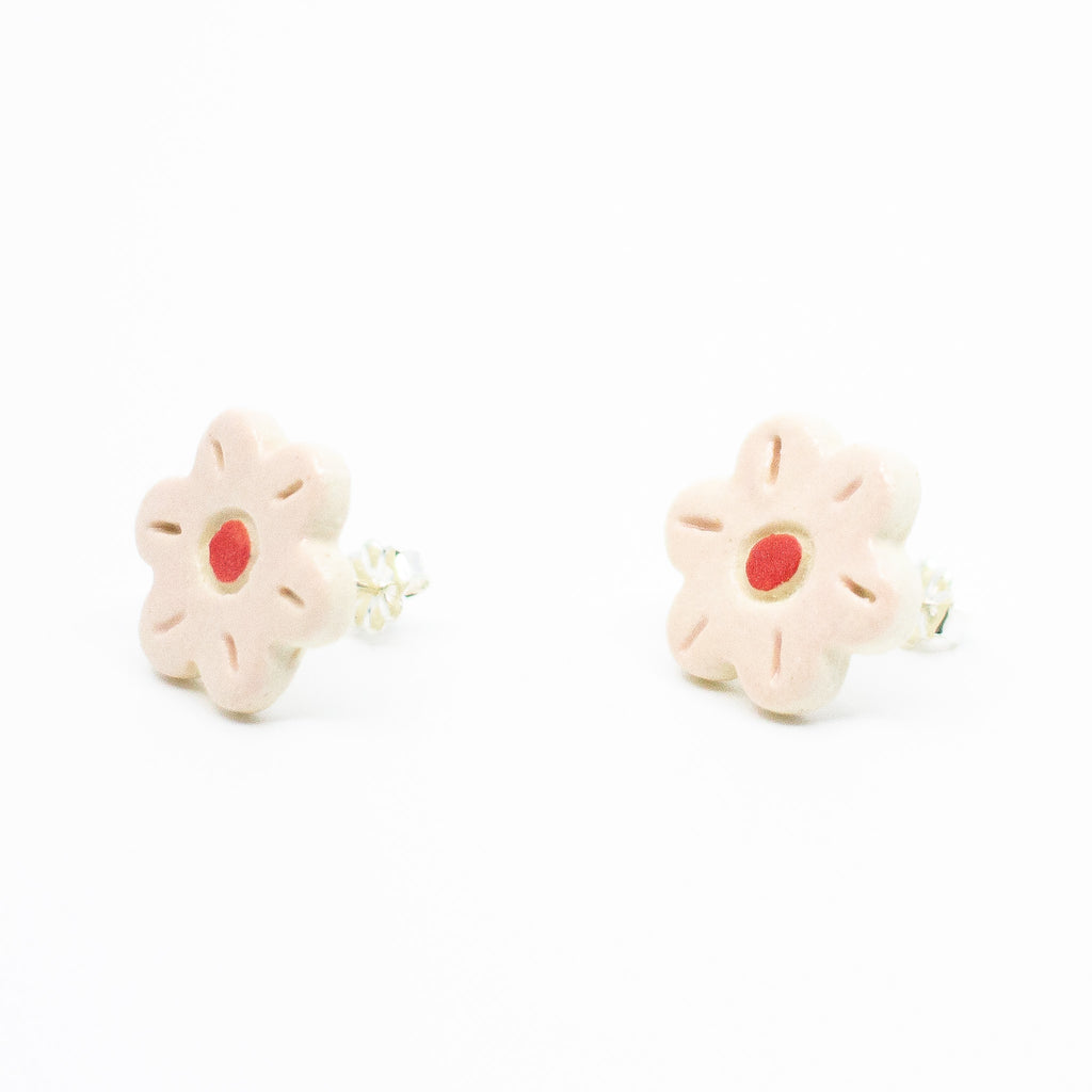 A photo of the rose stud earrings. Ceramic earrings with a flower shape and rose colour leaves with a red centre. Side view also shows sterling silver stud backings. 