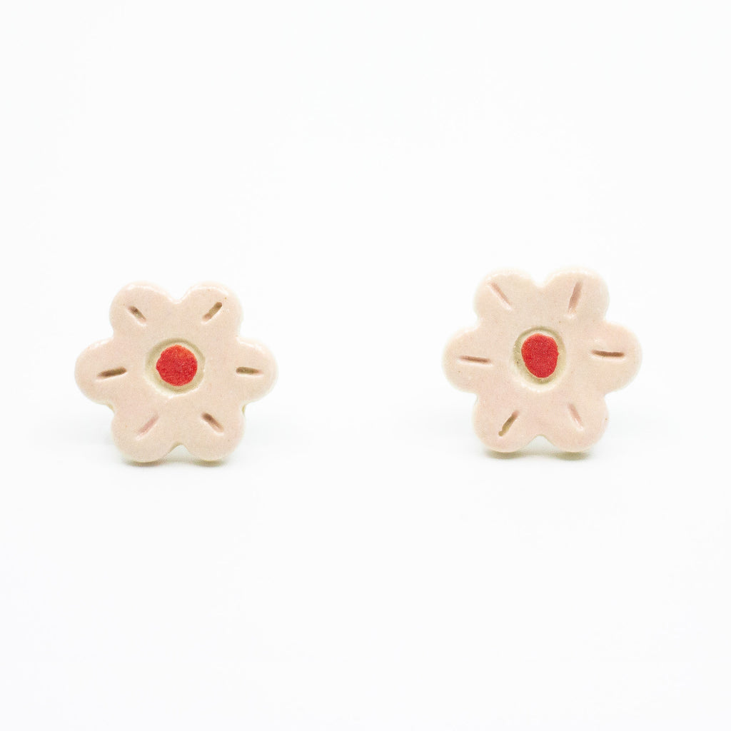 A photo of the rose stud earrings. Ceramic earrings with a flower shape and rose colour leaves with a red centre.